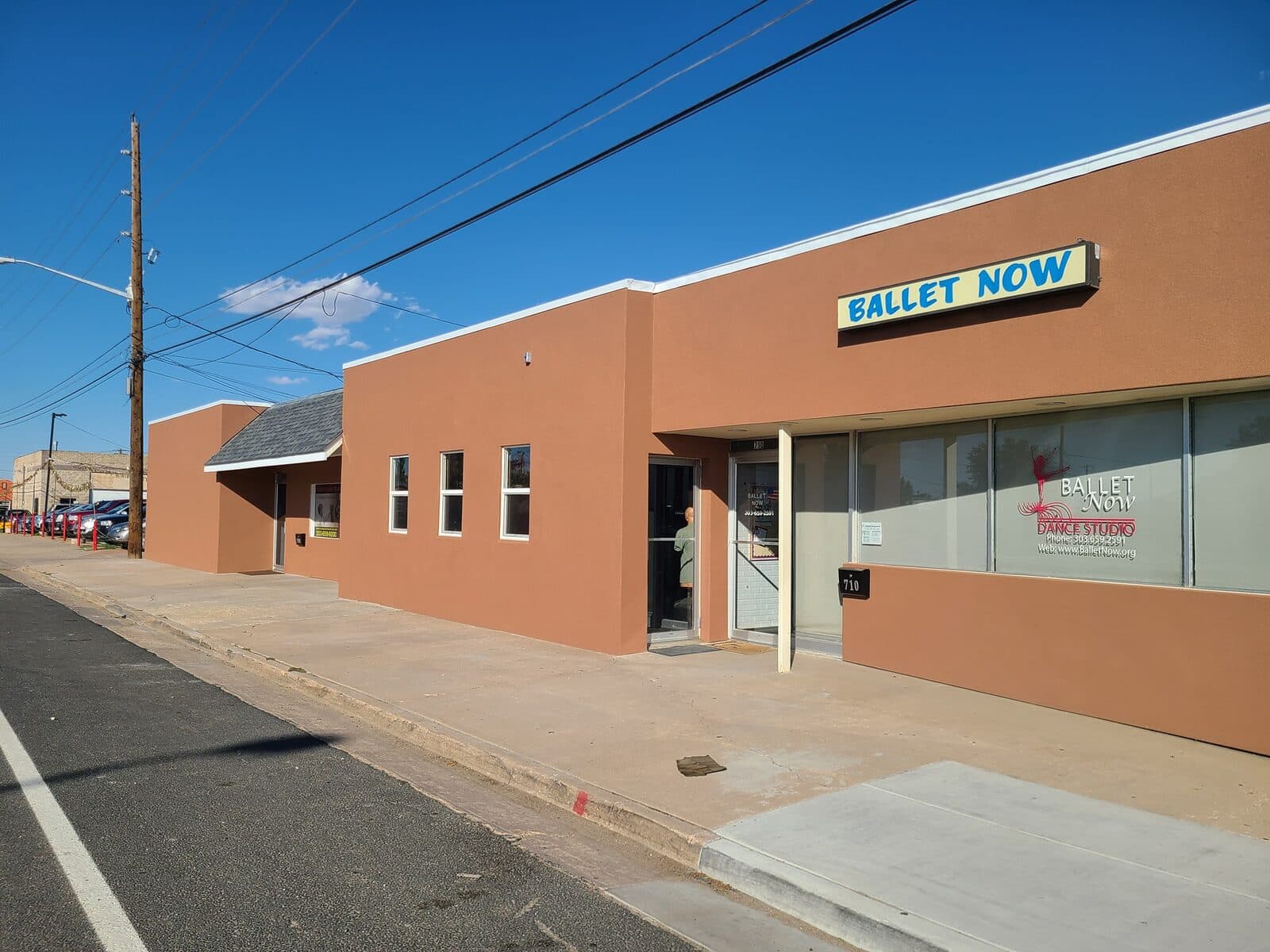 A commercial storefront building refinished in terracotta stucco along a Colorado main street