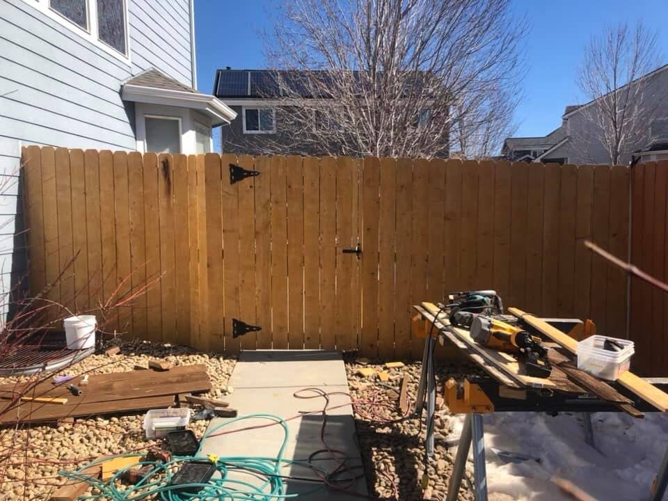 A newly built cedar privacy fence with a gate, installed in a Colorado back yard
